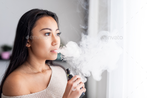 Casual asian woman vaping electronic cigarette at home Stock Photo